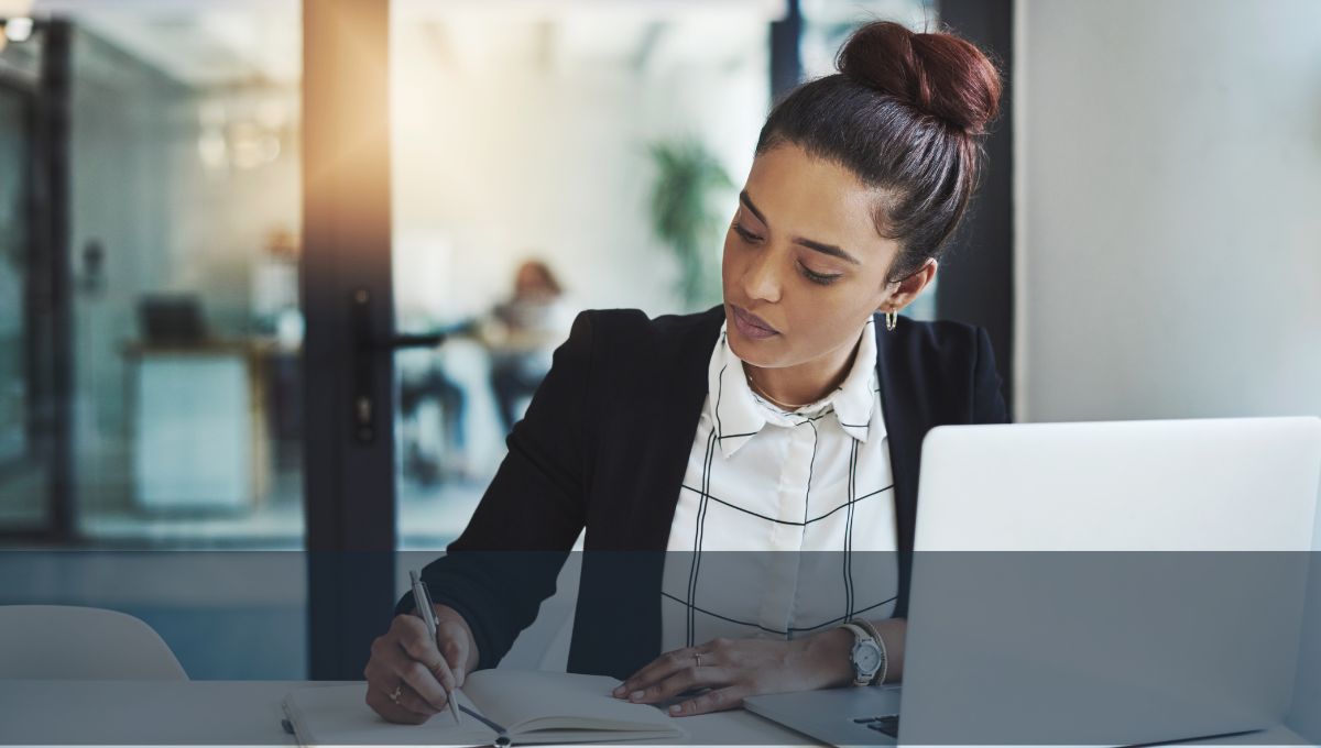 dark haired woman with a bun looking down at her work in the office, How to Sell as a Spiritual Entrepreneur dark haired woman with a bun looking down at her work in the office, How to Sell as a Spiritual Entrepreneur